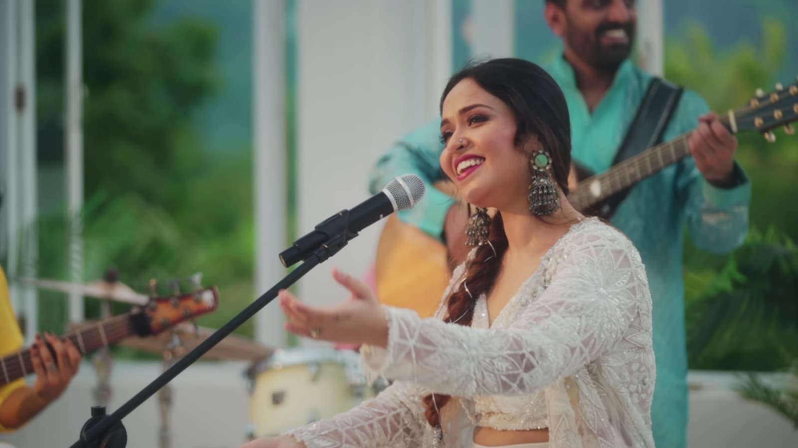 Aishwarya Anand performing on stage with dramatic amber lighting, arms outstretched